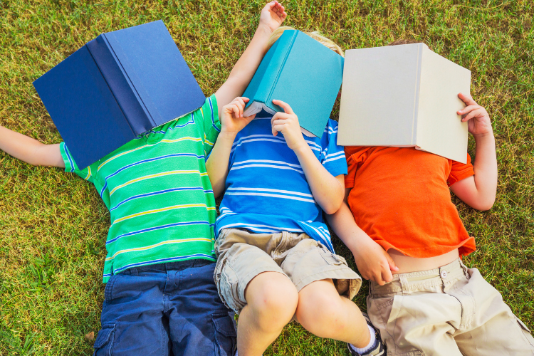 Kids Reading Books Lying on Grass